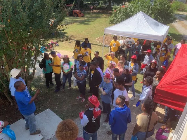 Volunteers and neighbors gathered under a canopy at a farm signup event